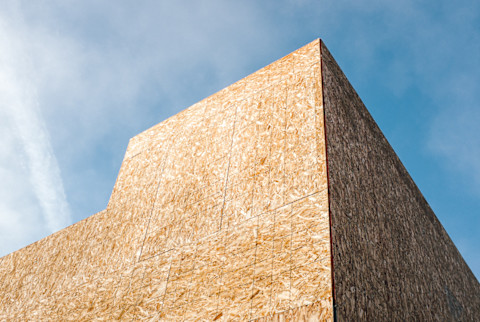 Low angle view of partially completed house under construction, particle board exterior Low angle view of partially completed house under construction, particle board exterior