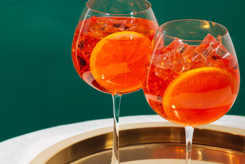 aperol spritz on a gold platter and green background