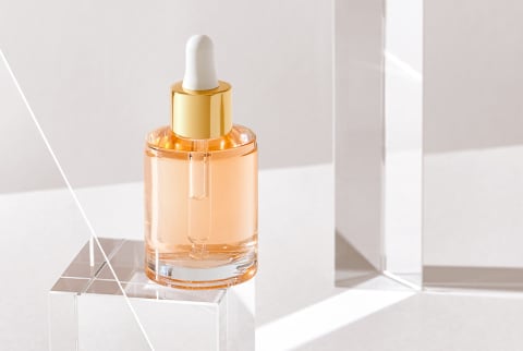 Clear Beauty Bottle with Dropper on a Glass Cube in Studio