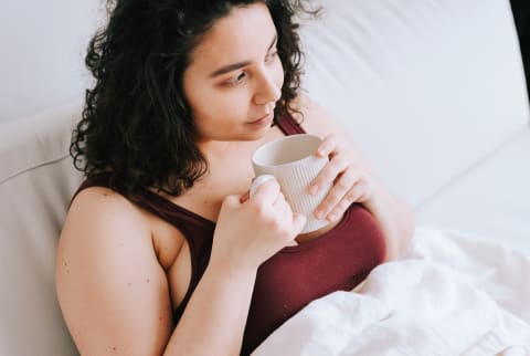 Young Woman Enjoying A Hot Drink In Bed