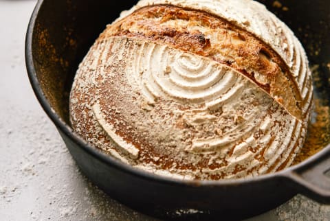 A freshly baked loaf of sourdough bread in a cast iron pot