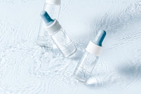 Clear Bottles of Serum on a Blue Background