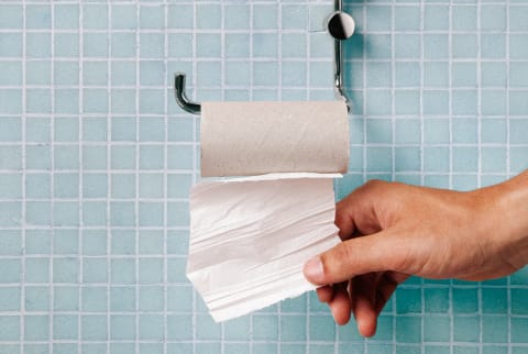 Hand pulling last square of toilet paper from the roll Hand pulling last square of toilet paper from the roll