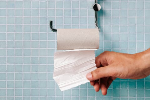 Hand pulling last square of toilet paper from the roll