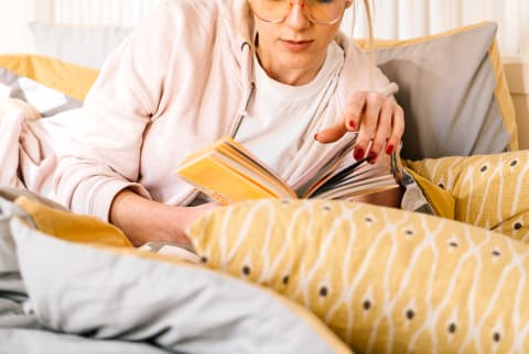 Young Woman Reading a Book In Bed