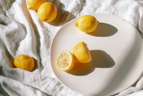 Freshly Cut Lemons on a Plate and Messy Tablecloth in Sunlight
