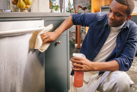 Man Wiping Down a Dishwasher with All Natural Household Cleaner