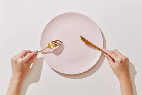 Hand with Fork and Knife and Empty Plate