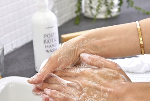 Woman washing her hands with mindbodygreen post biotic handwash