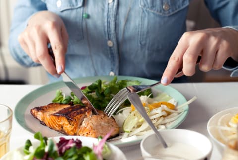 Woman cutting into a salmon filet