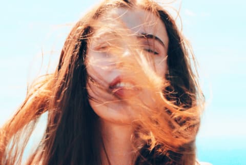 Girl outside with wind blowing hair into face