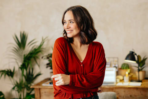 Woman Smiling with Her Arms Crossed in a Casual Office