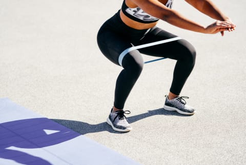 Woman Doing Squats Outdoors with a Resistance Band