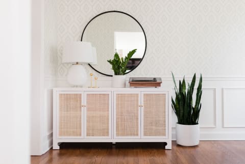 Sideboard table in dining room with record player, brass candlesticks, and plants