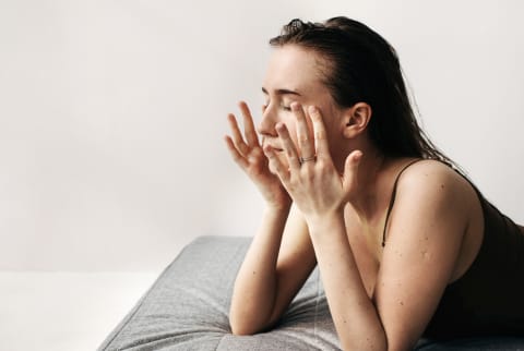 Tired Female Rubbing Eyes On Bed