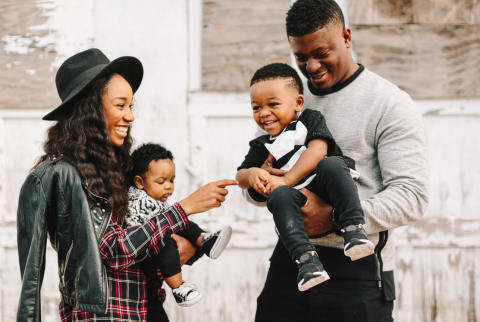 A Family Of Four Playing And Having Fun Outdoors Together