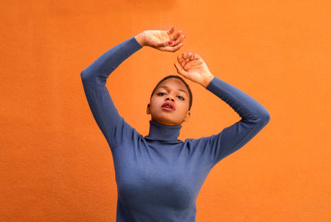 Portrait of a woman in a blue sweater on an orange background