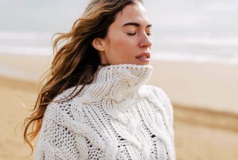 Woman outdoors on beach in sweater during fall / winter