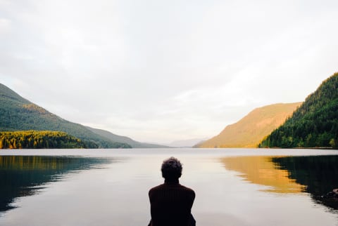 Silhouette of a Man Sitting By a Lake