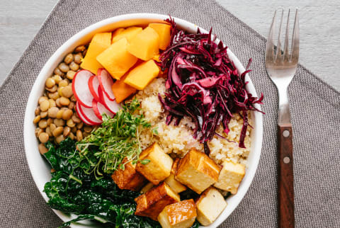 Bowl with healthy vegetabls and tofu. Ingredients: quinoa, lentils, dinosaur kale, smoked tofu, red cabbage, winter squash, radish, cress sprouts