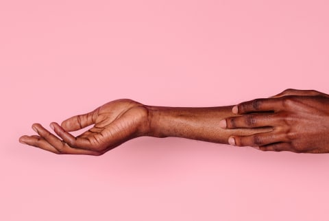 Man Touching His Forearm With Hand On Pink Background