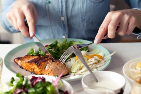 Woman cutting into a salmon filet