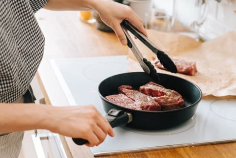 Woman Cooking a Steak successful a Cast Iron Skillet