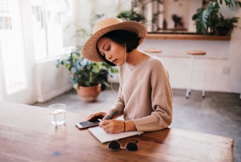 Woman Sitting at a Table Journaling with a Glass of Water