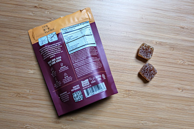 Lazarus Naturals CBD Sleep Gummies open packages next to two gummies on wood table