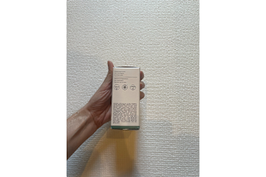 Biossance Squalane + Copper Peptide Rapid Plumping Serum box held in a tester's hand against the wall back surface of the box