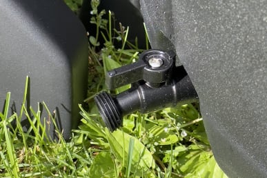 Close-up photo of Ice Barrel drain with spout turned off above green grass