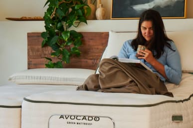 Avocado Mattress Eco Pro Base in a bedroom with a woman reading and having coffee