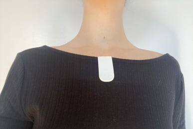 apollo neuro device in white attached to tester's t-shirt collar
