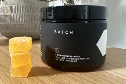 Batch Gold Reserve Gummies on Desk with small stack of organic gummies