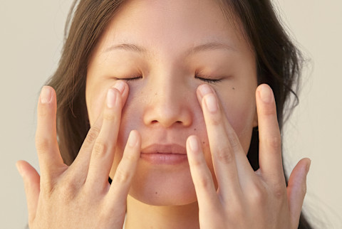asian woman patting under eye area asian woman patting under eye area