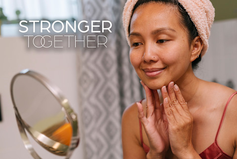 Woman washing her face in the mirror - Stronger Together Woman washing her face in the mirror - Stronger Together