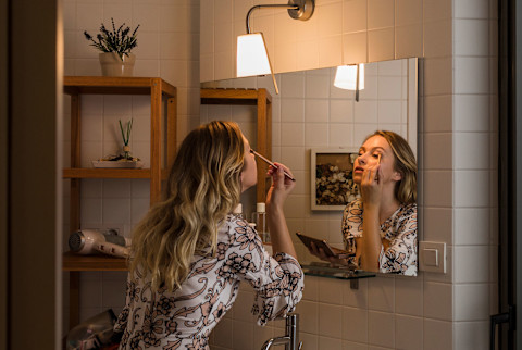 woman applying makeup in the mirror