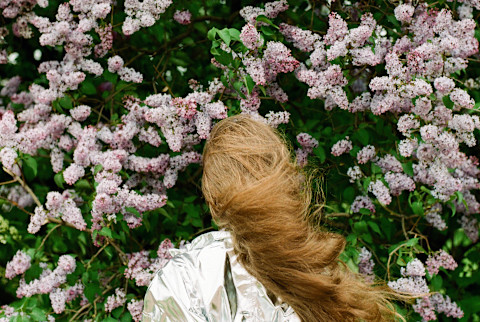 Woman standing in front of lilac bush Woman standing in front of lilac bush