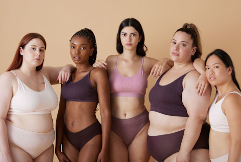 Diverse happy women in beige underwear clothes on a beige background