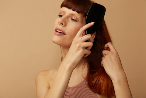 woman with red hair brushing it with a comb woman with red hair brushing it with a comb