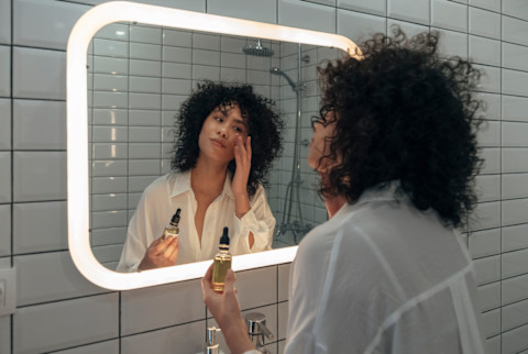 Woman doing skincare in the mirror Woman doing skincare in the mirror