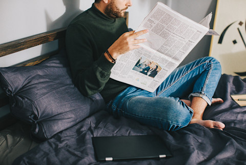 Unrecognizable Man Reading the Newspaper in Bed Unrecognizable Man Reading the Newspaper in Bed