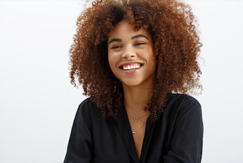Black woman with curly brunette hair, smiling against a white background. Black woman with curly brunette hair, smiling against a white background.