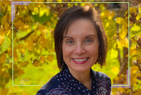 woman smiling in front of fall foliage