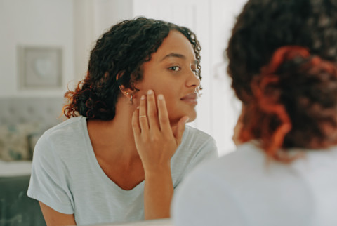 Woman Checking Her Skin in the Bathroom Mirror Woman Checking Her Skin in the Bathroom Mirror