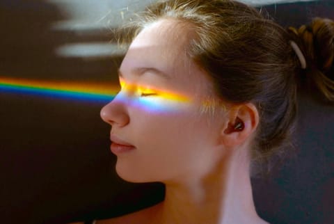 girl with rainbow light spectrum hitting her face