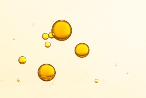 drips of dark yellow oil on peach background
