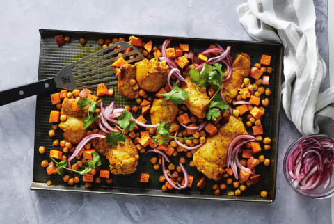 Baking sheet with chicken, sweet potatoes, chickpeas, red onion and parsely. 