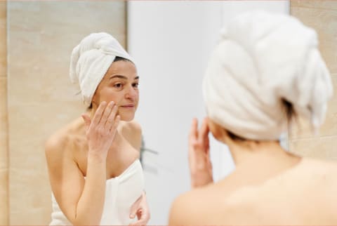 woman touching face in mirror