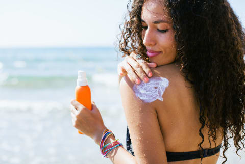 Woman Applying Sunscreen Lotion On Her Shoulder.